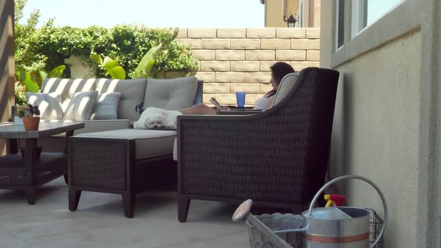 Relaxing female & sleepy dog reading tablet in home garden