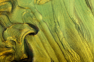 Beautiful stains of liquid nail polish,fluid art technique.Gold marble background.Nail lacquer flow...