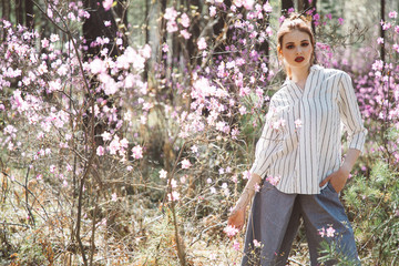 A girl dressed in Japanese style in a flowering forest among pink flowers