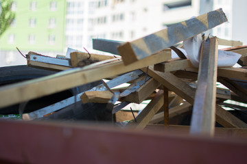 a litterless metal container without a cover is full of construction debris and waste standing in the middle of the street next to a building under construction in the city in the sun