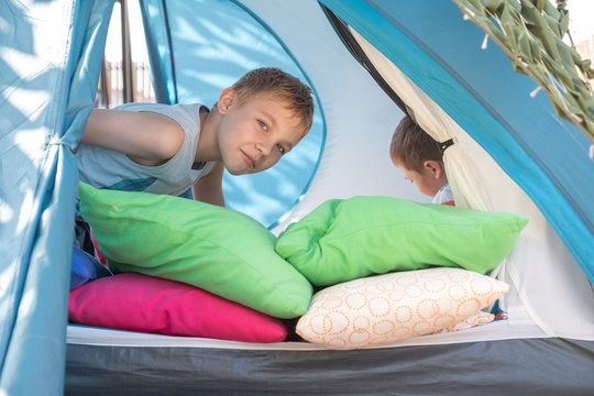 Cute Boys Playing With Pillow Inside Tent At Backyard