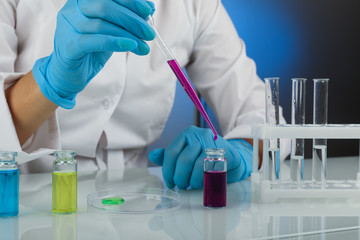Biochemist`s hands in gloves are conducting chemical experiments in lab. chemist works with lab...