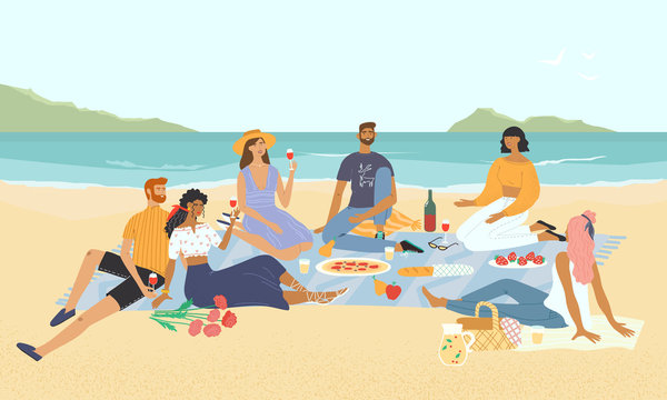 Smiling friends relaxing at a picnic on the seashore. Happy men and women drinking wine and eating food on the beach. Group of stylish people having lunch with marine landscape view on the background.