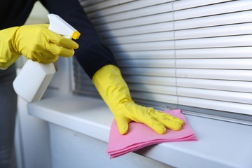 cleaner's hands in yellow rubber gloves doing disinfection cleaning with detergent spray and rag. preventive measures against virus infection
