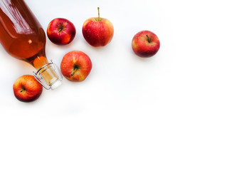Top view of a bottle and glass with natural apple juice. Apple drink made from fermented fruit drink and organic apples on white, banner. Homemade apple juice. Copy space.