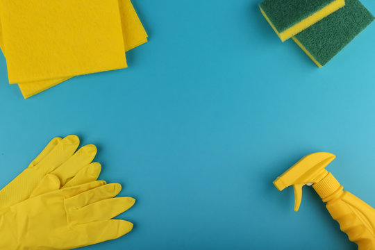 Yellow Spray Bottle Detergent Or Sanitizer, Yellow Cleaning Cloth And Gloves On Blue Background Flat Lay With Copy Space.