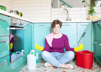 Mams home quarantine concept. A smiling young Caucasian woman in rubber gloves among detergents and...