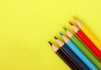 Colored pencils on yellow background. 6 colors Black, blue, blue, green, red, yellow. Pencils are well-honed. Flatlay. Isolated. Art. Art therapy. Leisure. Pencils are placed in the lower right corner