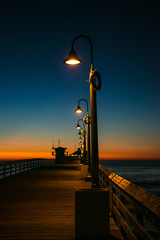 Obraz premium Atardecer en muelle con lámparas