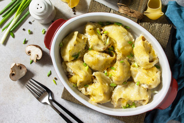 Italian pasta Conchiglioni Rigati stuffed with chicken, royal champignons, baked with cheese in bechamel sauce on a gray stone countertop. Top view flat lay background.