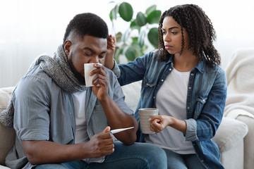 Caring African American Woman Looking After Her Ill Boyfriend At Home