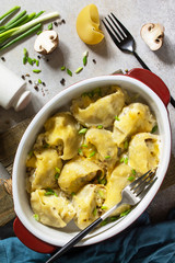 Italian pasta Conchiglioni Rigati stuffed with chicken, royal champignons, baked with cheese in bechamel sauce on a gray stone countertop. Top view flat lay background.