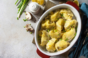 Italian pasta Conchiglioni Rigati stuffed with chicken, royal champignons, baked with cheese in bechamel sauce on a gray stone countertop. Top view flat lay background. Copy space.