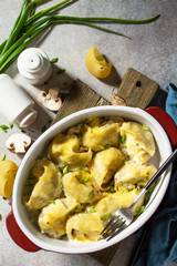 Italian pasta Conchiglioni Rigati stuffed with chicken, royal champignons, baked with cheese in bechamel sauce on a gray stone countertop. Top view flat lay background. Copy space.
