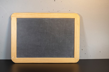 Black scratch board in a wooden frame on a black surface on a gray background.