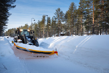 Kittila, Finland - Feb 23, 2020: Snow plow tractor is cleaning city walkway that covered by a lot...