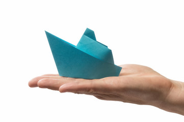 Blue paper ship in human palm. Concept of booking cruise tour and cargo transportation. Isolated on...