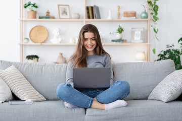 Positive girl looking for job online from home, using laptop