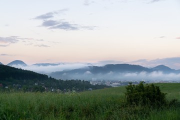 Sunrise and sunset, beautiful clouds over the meadow, hills and buildings in the town. Slovakia