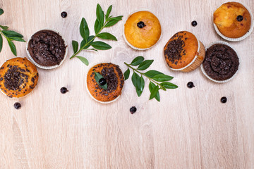 Chocolate muffin and nut muffin, homemade bakery on dark background. Muffin with blueberries on a wooden table. Fresh berries and sweet pastries on the board.