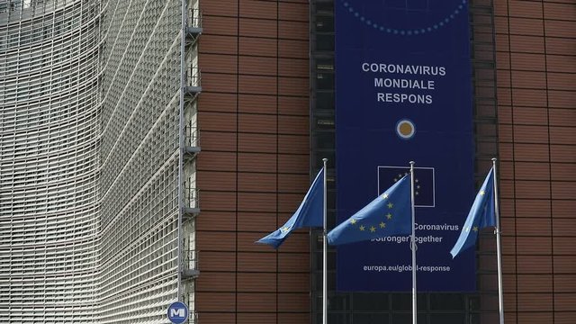 BRUSSELS, Belgium -May 6, 2020: 
European flags in the wind in front of The "Coronavirus - Global Response" banner on the front of the Berlaymont building, the headquarters of the European Commission - Powered by Adobe
