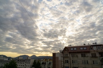 Sunrise and sunset, beautiful clouds over the meadow, hills and buildings in the town. Slovakia