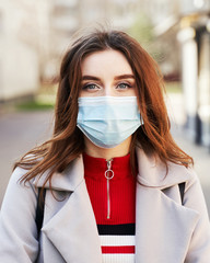 Young woman with beautiful blue eyes and disheveled hair wearing protection face mask against coronavirus MERS-Cov, Novel coronavirus 2019-nCoV. Concept of coronavirus quarantine and pandemic.