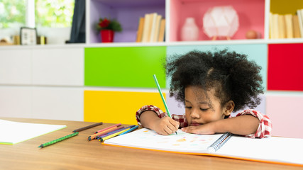 Young African American kid girl drawing with colored pencil, preschool child study at home school. Children education, self isolation, coronavirus outbreak social distancing or homeschooling concept