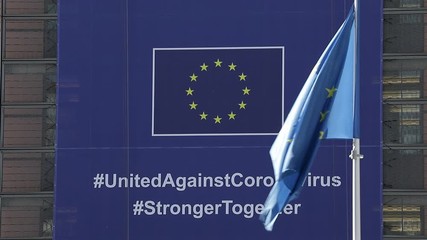 BRUSSELS, Belgium -May 6, 2020: 
European flags in the wind in front of The "Coronavirus - Global Response" banner on the front of the Berlaymont building, the headquarters of the European Commission - Powered by Adobe