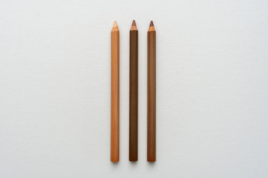 Three neutral color pencils on a white canvas