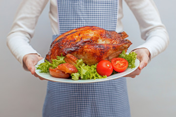 the cook holds a beautifully served plate with baked bird, duck, chicken or turkey stuffed with...