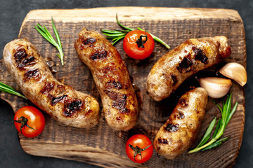 grilled sausage with spices and rosemary on
cutting board on stone background