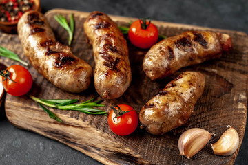grilled sausage with spices and rosemary on
cutting board on stone background