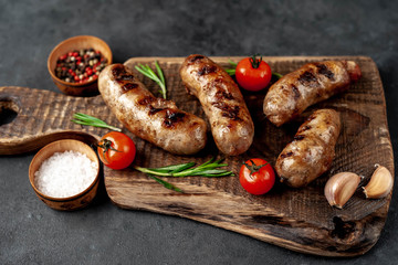 grilled sausage with spices and rosemary on
cutting board on stone background