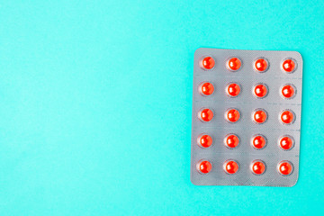Orange pills in a blister on a turquoise background with copyspace