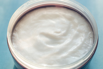 cream in container on blue background