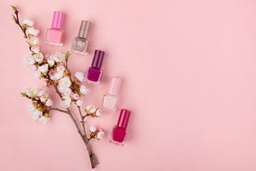 Obraz na płótnie Canvas Nail Polish on a pink background. Manicure set with Sakura flowers flat lay. Close up с пространством для текста.