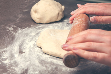 cook woman hands roll out the dough on the table
