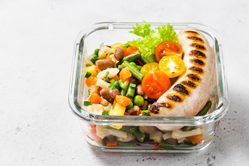 Grilled sausage and steamed vegetables in glass container. Top view, space for text.