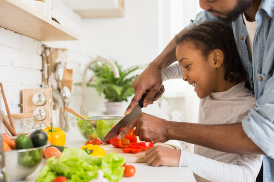 Cropped image of black father and daughter cutting vegetables