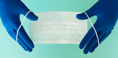 A pair of thin blue medical latex gloves and face shield on a white background. Disposable rubber medical gloves and mask. Protective subjects. Remedies.