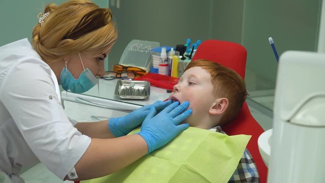 Happy red-haired boy at reception at dentist in dental chair. Pediatric dentistry
