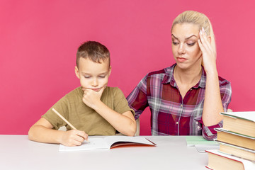 Homeschooling and distance education for students. Little child boy learn with mum at home school. Boy student doing homework helped by his mother.