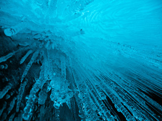 Blue ice background. Ice stalactites stalagmites. The ice of lake Baikal