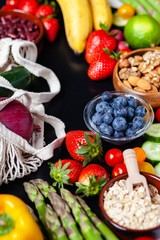 Concept of healthy food, clean eating. Organic fresh ingredients for cooking simple delicious vegetarian meal. Source of vitamins. Bright colors. Top view black background.