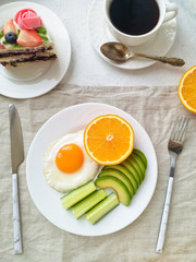Egg, avocado, cucumber and orange served for Breakfast on a textile napkin on a light background top view. The concept of proper nutrition.