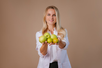 young female dietitian doctor smiles, holding green apples. space for text