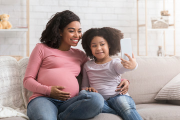 Little African Girl Taking Selfie With Happy Pregnant Mom At Home