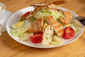 grilled chicken salad with croutons on a white round plate