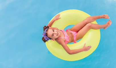 Optimistic child resting on tube in pool